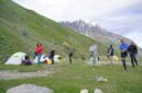 Pemandangan padang rumput pegunungan Tian Shan di Kyrgyzstan dengan tenda tradisional yurt di bawah naungan puncak bersalju.