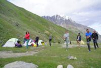 Pemandangan padang rumput pegunungan Tian Shan di Kyrgyzstan dengan tenda tradisional yurt di bawah naungan puncak bersalju.