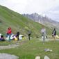 Pemandangan padang rumput pegunungan Tian Shan di Kyrgyzstan dengan tenda tradisional yurt di bawah naungan puncak bersalju.