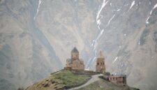 Gereja Gergeti Trinity berdiri anggun di latar belakang hamparan Pegunungan Kaukasus dan Puncak Gunung Kazbek di Georgia.