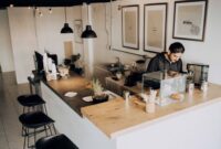 Seorang pelancong menikmati momen santai di sebuah kedai kopi lokal sembari merencanakan rute perjalanan dengan barang bawaan yang ringkas dan efisien.