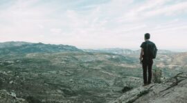Seorang pendaki berdiri menatap hamparan lembah dan puncak es abadi di Patagonia Chile, menggambarkan tantangan serta keindahan alam liar yang menjadi tujuan favorit para penjelajah dunia.