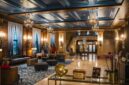 Interior lobi hotel bersejarah berarsitektur klasik yang menampilkan perpaduan lampu kristal dan furnitur kuno terawat rapi.