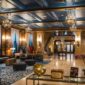 Interior lobi hotel bersejarah berarsitektur klasik yang menampilkan perpaduan lampu kristal dan furnitur kuno terawat rapi.