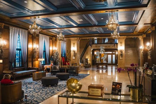 Interior lobi hotel bersejarah berarsitektur klasik yang menampilkan perpaduan lampu kristal dan furnitur kuno terawat rapi.