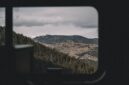 Penumpang kereta wisata panorama menikmati keindahan pemandangan hijau perbukitan melalui jendela kaca berukuran besar sepanjang perjalanan.