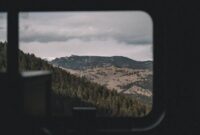 Penumpang kereta wisata panorama menikmati keindahan pemandangan hijau perbukitan melalui jendela kaca berukuran besar sepanjang perjalanan.