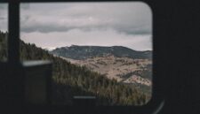 Penumpang kereta wisata panorama menikmati keindahan pemandangan hijau perbukitan melalui jendela kaca berukuran besar sepanjang perjalanan.