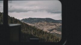 Penumpang kereta wisata panorama menikmati keindahan pemandangan hijau perbukitan melalui jendela kaca berukuran besar sepanjang perjalanan.