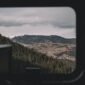 Penumpang kereta wisata panorama menikmati keindahan pemandangan hijau perbukitan melalui jendela kaca berukuran besar sepanjang perjalanan.