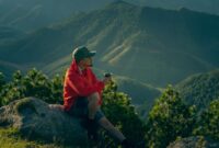 Seorang pelancong menikmati pemandangan alam pegunungan yang sejuk dan asri, mencerminkan tren wisata global yang kini lebih berfokus pada ketenangan jiwa dan kenyamanan iklim.