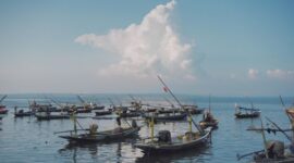 Sebuah perahu kayu tradisional melintas santai di antara tebing-tebing karang gugusan pulau Raja Ampat saat matahari mulai terbenam di ufuk barat. Lanskap bahari ini menjadi salah satu daya tarik utama pelancongan alam di Indonesia bagian timur.