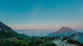 Sebuah kendaraan melintasi jalur darat dengan latar pemandangan alam pegunungan Indonesia yang asri. Kemudahan jalan menuju lokasi wisata kini memberikan kenyamanan lebih bagi para wisatawan domestik.