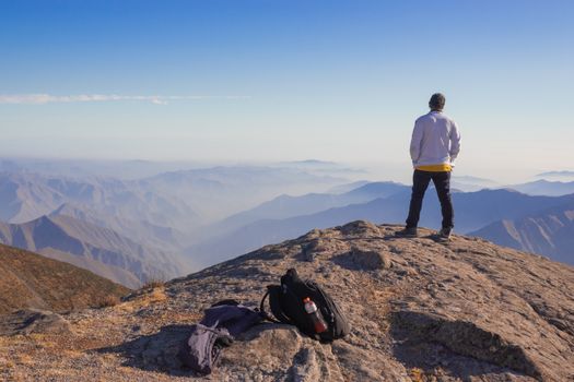 Seorang pelancong menikmati ketenangan pemandangan alam pegunungan yang sejuk dan asri, mencerminkan maraknya tren *coolcation* dan *slow travel* di kalangan wisatawan global.