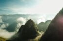 Penumpang menikmati pemandangan alam memukau dari balik jendela kereta api panorama yang melintasi kawasan pegunungan hijau saat fajar tiba.