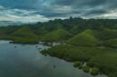 Pemandangan lanskap perbukitan hijau dan perumahan adat khas Sumba di Nusa Tenggara Timur yang menyajikan ketenangan alam pedalaman bagi para penjelajah.