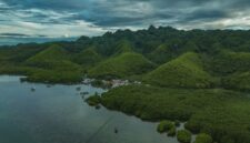 Pemandangan lanskap perbukitan hijau dan perumahan adat khas Sumba di Nusa Tenggara Timur yang menyajikan ketenangan alam pedalaman bagi para penjelajah.