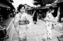 Suasana tenang di salah satu lorong bersejarah di kawasan Gion, Kyoto, di mana para pejalan kaki dapat merasakan kehangatan arsitektur kayu tradisional di tengah rinai hujan tipis.