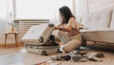 Seorang pelancong sedang merapikan pakaian secara terorganisasi ke dalam koper ringkas sebelum memulai perjalanan. Pengemasan barang yang efisien menjadi kunci utama kenyamanan dan kelincahan selama berlibur.