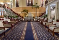 Suasana lobi hotel klasik dengan sentuhan lampu gantung megah yang menggambarkan keanggunan era awal industri perhotelan modern di Eropa.