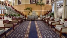 Suasana lobi hotel klasik dengan sentuhan lampu gantung megah yang menggambarkan keanggunan era awal industri perhotelan modern di Eropa.