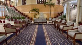 Suasana lobi hotel klasik dengan sentuhan lampu gantung megah yang menggambarkan keanggunan era awal industri perhotelan modern di Eropa.