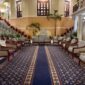 Suasana lobi hotel klasik dengan sentuhan lampu gantung megah yang menggambarkan keanggunan era awal industri perhotelan modern di Eropa.