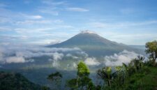 Pemandangan matahari terbit memancar di atas lautan tenang Banda Neira dengan latar belakang peninggalan bersejarah dan kemegahan puncak Gunung Api Banda.