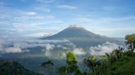 Pemandangan matahari terbit memancar di atas lautan tenang Banda Neira dengan latar belakang peninggalan bersejarah dan kemegahan puncak Gunung Api Banda.