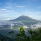 Pemandangan matahari terbit memancar di atas lautan tenang Banda Neira dengan latar belakang peninggalan bersejarah dan kemegahan puncak Gunung Api Banda.