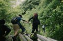 Seorang penjelajah menikmati pemandangan hamparan perbukitan hijau dan lembah berbuai kabut tipis saat menikmati keheningan pagi di kawasan dataran tinggi Nusantara.