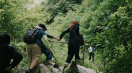 Seorang penjelajah menikmati pemandangan hamparan perbukitan hijau dan lembah berbuai kabut tipis saat menikmati keheningan pagi di kawasan dataran tinggi Nusantara.