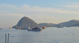 Pemandangan lanskap gugusan pulau-pulau kecil di kawasan pesisir Labuan Bajo saat matahari fajar menyingsing. Lautan biru jernih dan bukit savana keemasan menciptakan salah satu pemandangan bahari paling memukau di Nusantara.