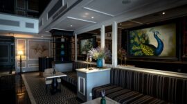 Keanggunan interior lobi hotel bersejarah yang memadukan detail arsitektur klasik zaman dulu dengan pencahayaan hangat, menciptakan atmosfer nostalgia yang mewah bagi para tamu.