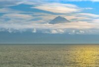 Pemandangan anggun Gunung Api Banda yang berdiri megah di seberang perairan tenang Banda Neira, Maluku, menjadikannya salah satu ikon wisata bahari dan sejarah paling memikat di Indonesia Timur.