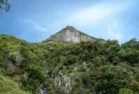 Pemandangan megah tebing granit menjulang tinggi yang mengapit hamparan sawah hijau di kawasan Lembah Harau, Sumatera Barat.