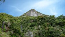 Pemandangan megah tebing granit menjulang tinggi yang mengapit hamparan sawah hijau di kawasan Lembah Harau, Sumatera Barat.