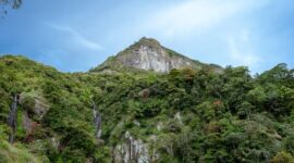 Pemandangan megah tebing granit menjulang tinggi yang mengapit hamparan sawah hijau di kawasan Lembah Harau, Sumatera Barat.
