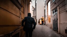 Seorang pengelana menikmati suasana pagi yang tenang di lorong bersejarah kota kuno sambil meresapi kehangatan budaya setempat.