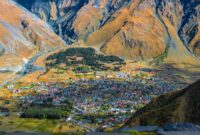 Gereja Gergeti Trinity berdiri megah dengan latar belakang pegunungan bersalju dan lanskap musim gugur di Kazbegi, Georgia. Foto ini mengabadikan salah satu pemandangan paling ikonik di wilayah Kaukasus.