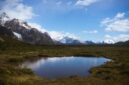 Seorang pendaki berjalan menyusuri jalur terjal dengan latar belakang puncak es dan danau alpine di kawasan Patagonia. Pemandangan lanskap murni ini menjadi salah satu daya tarik utama petualangan alam terbuka kelas dunia.