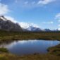 Seorang pendaki berjalan menyusuri jalur terjal dengan latar belakang puncak es dan danau alpine di kawasan Patagonia. Pemandangan lanskap murni ini menjadi salah satu daya tarik utama petualangan alam terbuka kelas dunia.