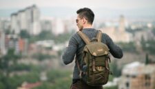 Seorang pelancong sedang mengemas barang bawaan dengan cermat ke dalam tas ransel sebelum memulai perjalanan akhir pekan yang santai.