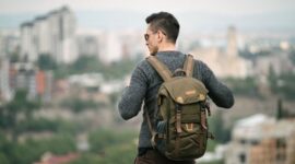 Seorang pelancong sedang mengemas barang bawaan dengan cermat ke dalam tas ransel sebelum memulai perjalanan akhir pekan yang santai.