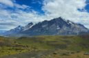 Seorang pendaki menikmati panorama keindahan puncak granit dan danau es di Taman Nasional Torres del Paine, Chili, yang menjadi salah satu destinasi petualangan terbaik dunia.