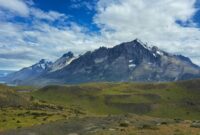 Seorang pendaki menikmati panorama keindahan puncak granit dan danau es di Taman Nasional Torres del Paine, Chili, yang menjadi salah satu destinasi petualangan terbaik dunia.