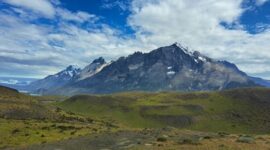 Seorang pendaki menikmati panorama keindahan puncak granit dan danau es di Taman Nasional Torres del Paine, Chili, yang menjadi salah satu destinasi petualangan terbaik dunia.