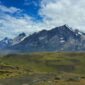 Seorang pendaki menikmati panorama keindahan puncak granit dan danau es di Taman Nasional Torres del Paine, Chili, yang menjadi salah satu destinasi petualangan terbaik dunia.