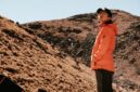 Seorang pendaki berdiri menatap megahnya gugusan puncak granit Torres del Paine di Chile yang dikelilingi lanskap subpolar liar dan danau glasial.
