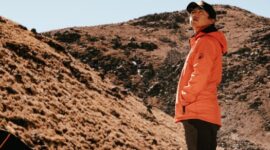 Seorang pendaki berdiri menatap megahnya gugusan puncak granit Torres del Paine di Chile yang dikelilingi lanskap subpolar liar dan danau glasial.